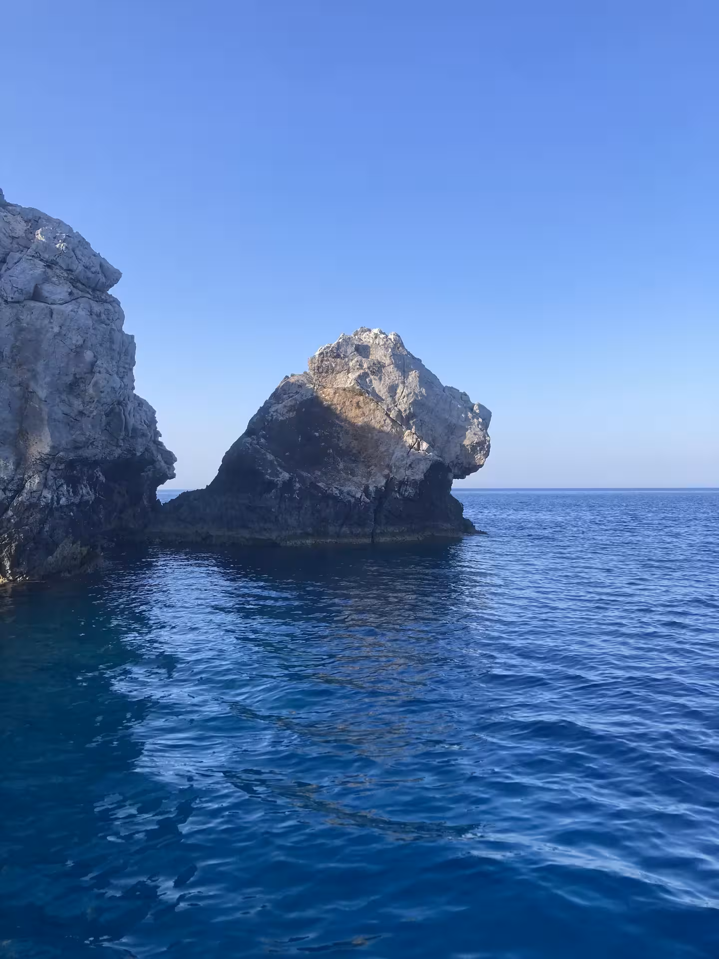 Rocky sea stack and deep blue water on Bayliner M17 2-hour cave tour with snorkelling stops