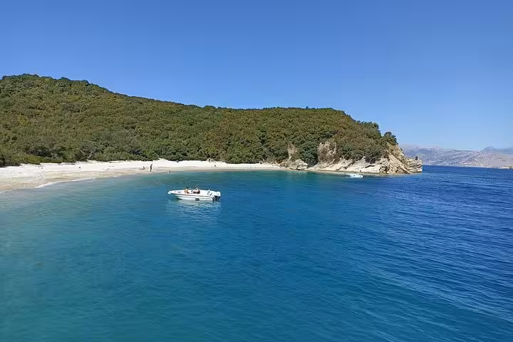 Small boat anchored off a quiet Ionian Sea bay on a locals BBQ boat trip, blue water and sandy beach