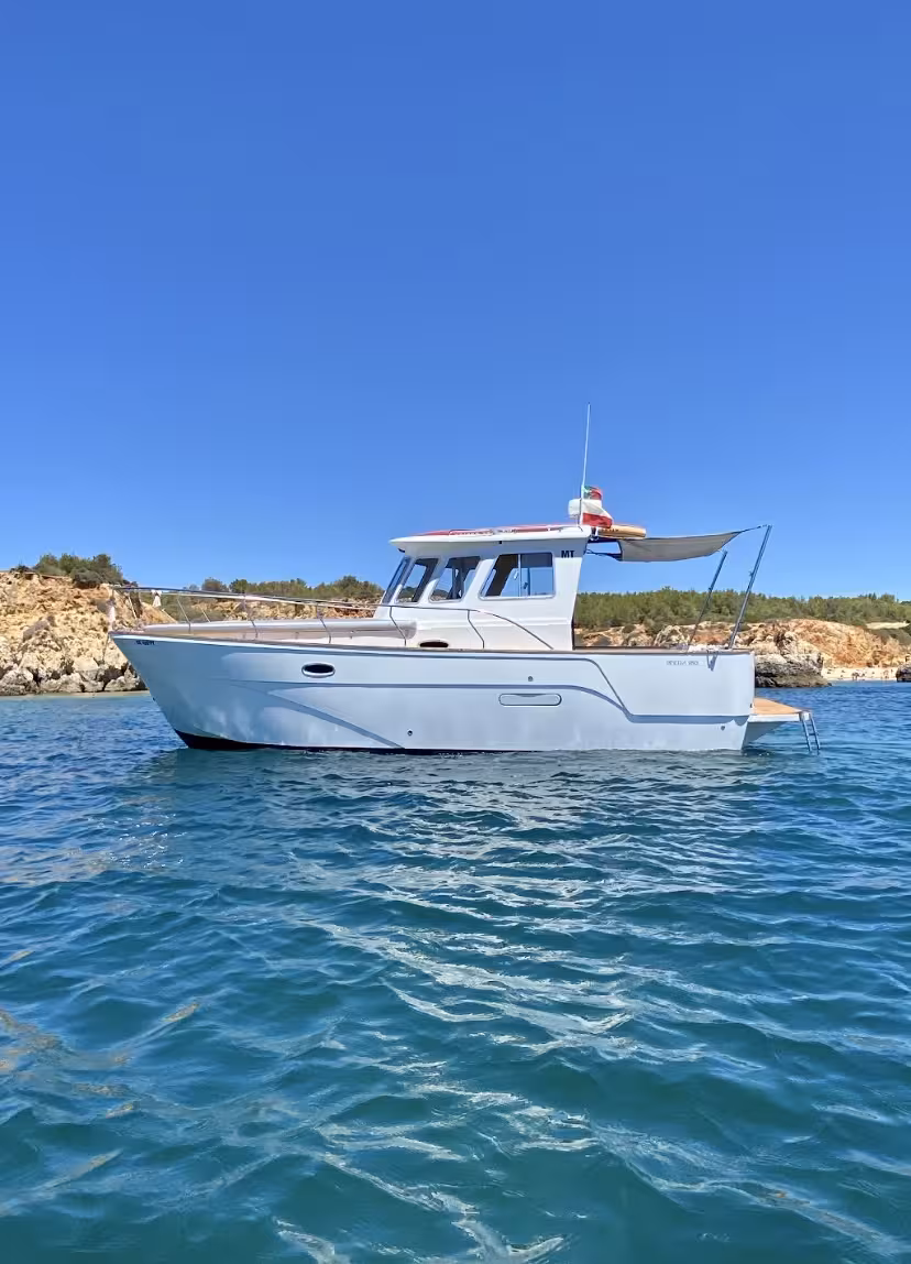 BE HAPPY yacht sailing near rocky cliffs under a clear blue sky, ideal for a private sunset cruise.
