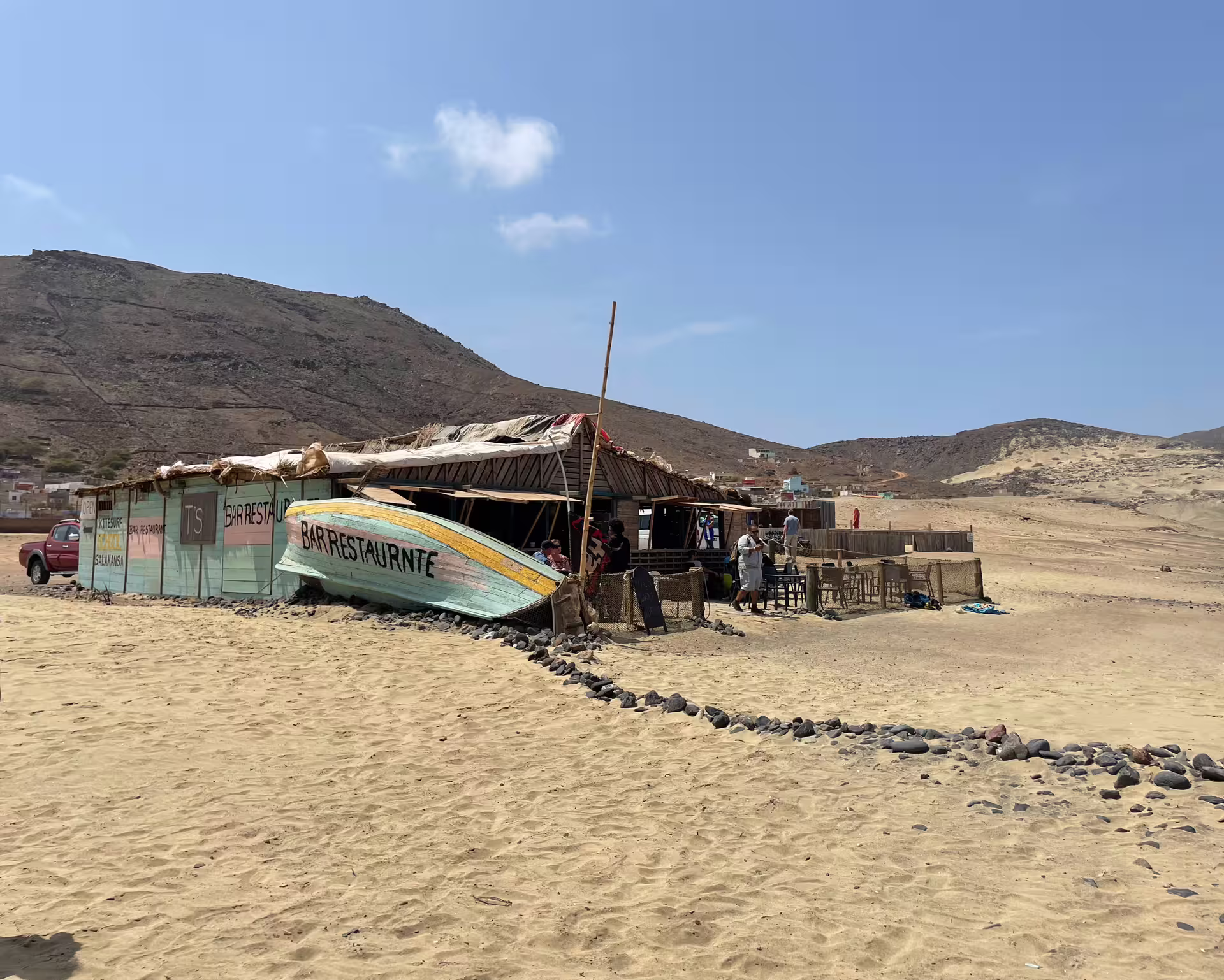 Rustic beachside restaurant on sandy shores with scenic hills in São Vicente, ideal for a full-day tour experience.