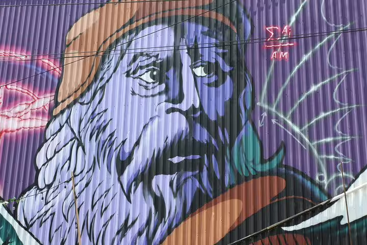Large street art mural of a bearded man painted in blue and purple tones on a corrugated metal wall in Ottawa