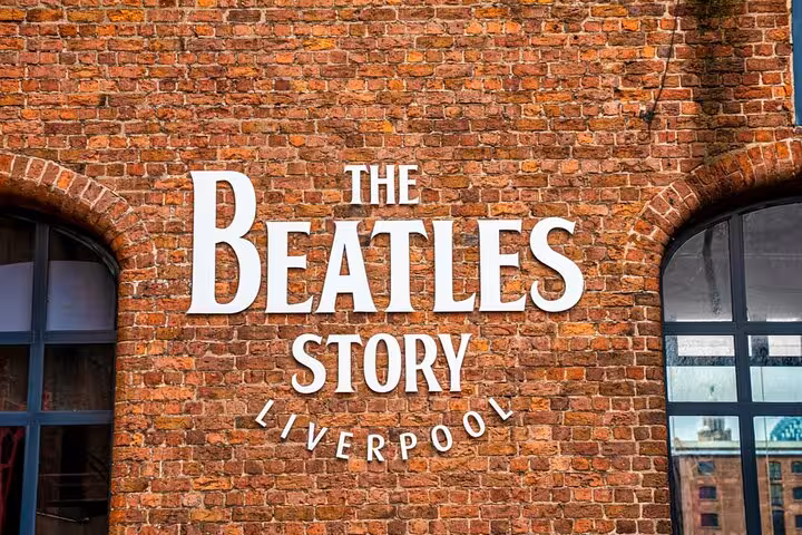 The Beatles Story Liverpool museum sign on a red brick wall with arched windows