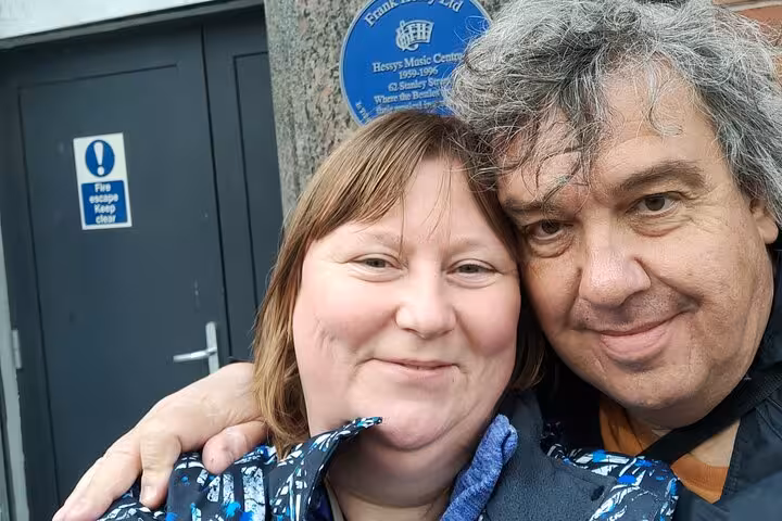 Couple smiling together in front of Hessys Music Centre blue heritage plaque in Liverpool