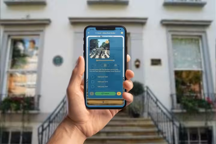 Hand holding smartphone with Beatles quiz app at Abbey Road Studios London