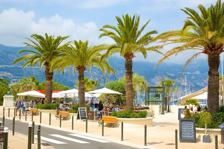 Palm-lined promenade with outdoor cafes and mountain views in Beaulieu-sur-Mer near Nice, French Riviera