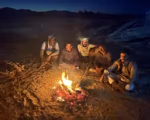 Four people sitting around a campfire at night in the desert during a Bedouin camp experience in Marsa Alam
