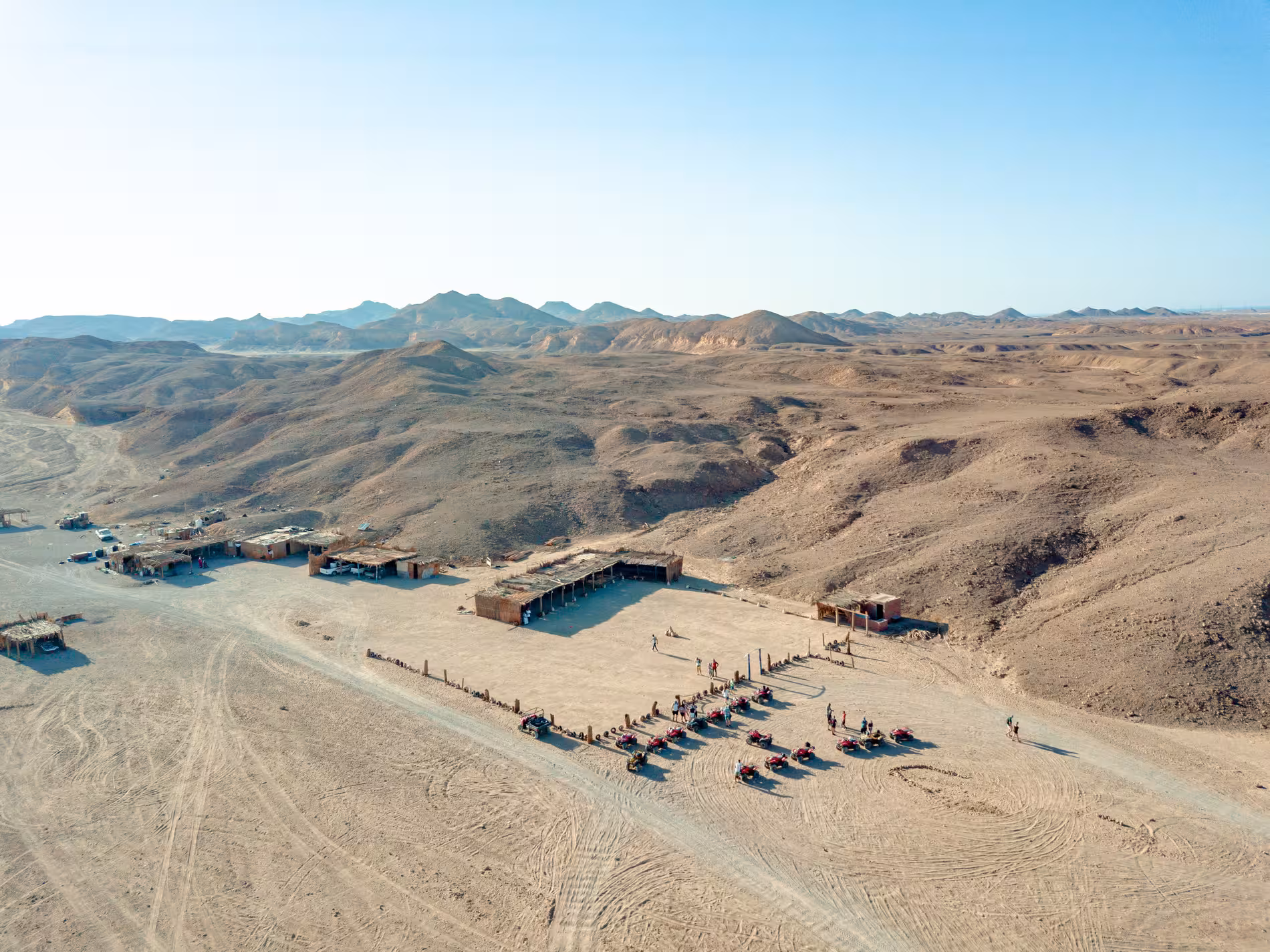 Aerial view of Bedouin desert camp with quad bikes and visitors in Marsa Alam rocky landscape