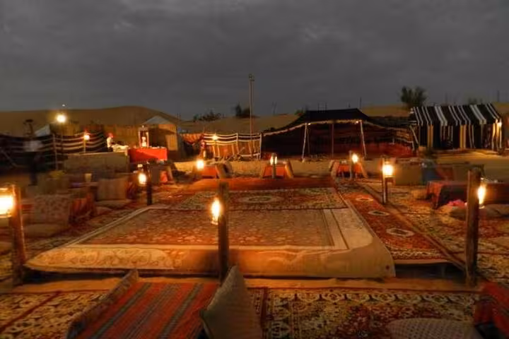 Traditional Bedouin camp in Marsa Alam desert lit by lanterns, carpets and seating for safari dinner night