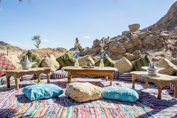 Traditional Bedouin seating area in Hurghada desert with rugs, low tables and tea setup before dinner show