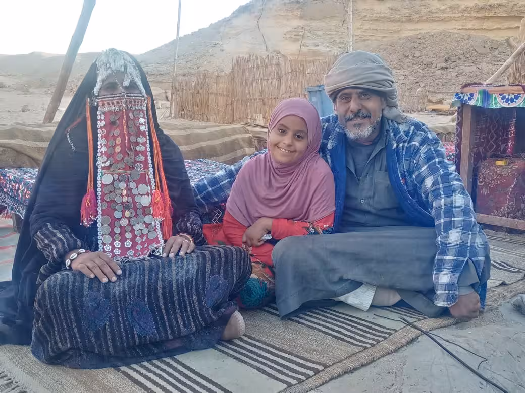 Bedouin family in traditional attire sitting on rugs in Hurghada desert camp