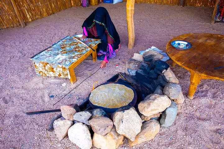 Bedouin woman baking flatbread on stone fire pit, Hurghada family safari quad jeep dinner shopping tour