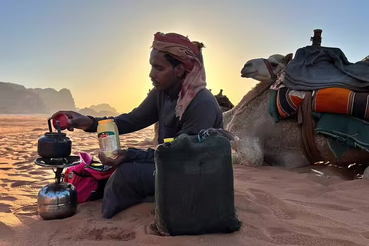 Bedouin guide brewing tea beside camel at sunset in Sinai desert on Sharm El Sheikh quad safari dinner tour
