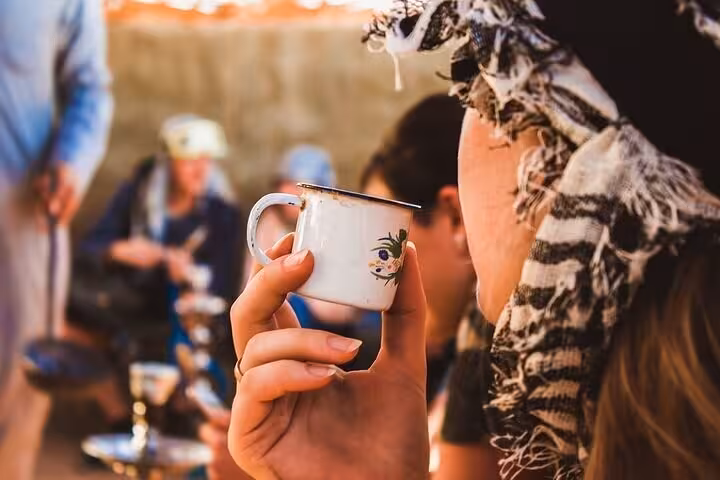 Guest sipping Bedouin tea at desert camp during Super Safari quad, camel ride, dinner and shows from Sharm
