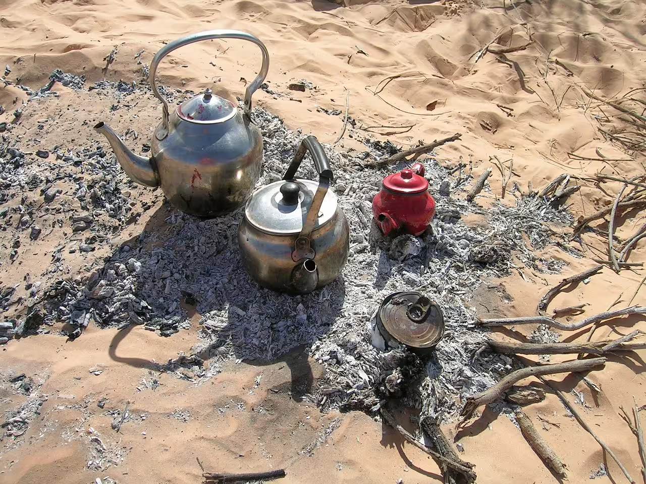 Bedouin tea kettles on hot desert embers during Mega Safari in Hurghada, authentic camp stop in Egypt