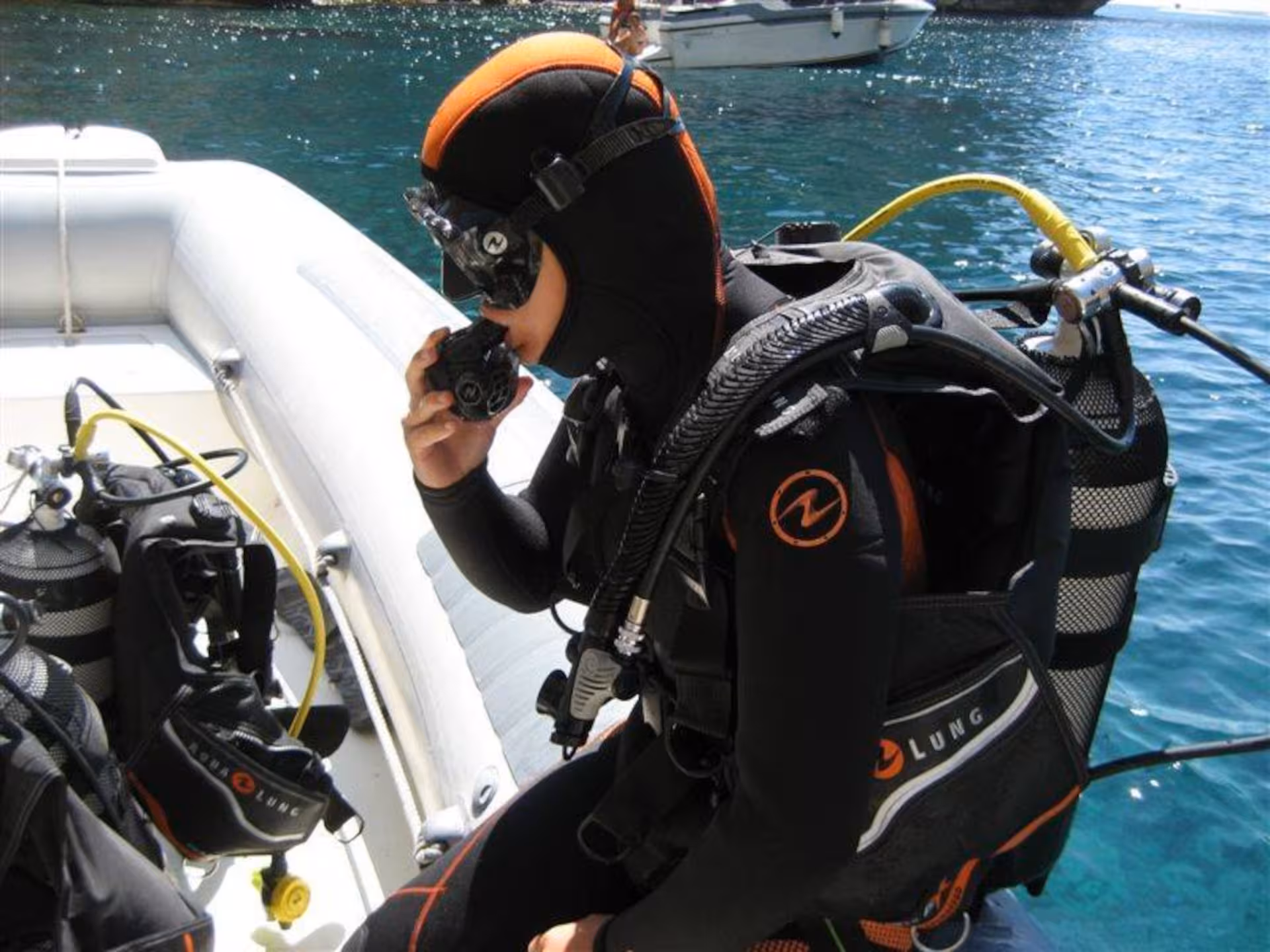 Beginner diver in Alghero preparing equipment on boat for discovery diving lesson.