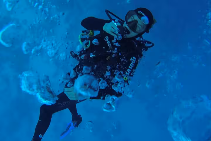 First-time scuba diver practicing buoyancy and breathing skills during beginner intro dive in crystal-clear ocean