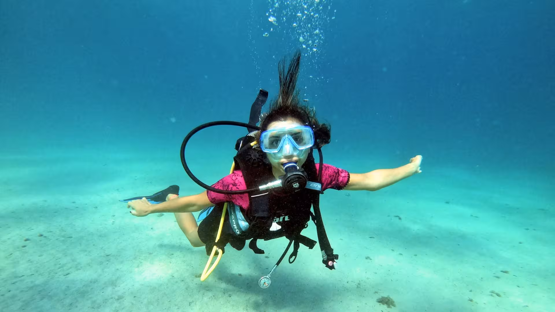 A beginner scuba diver in vibrant gear explores the crystal-clear waters of Cagliari, embracing a new adventure.