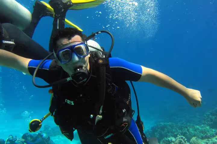 Beginner scuba diver with instructor over coral reef on an intro diving and snorkeling day trip in clear water