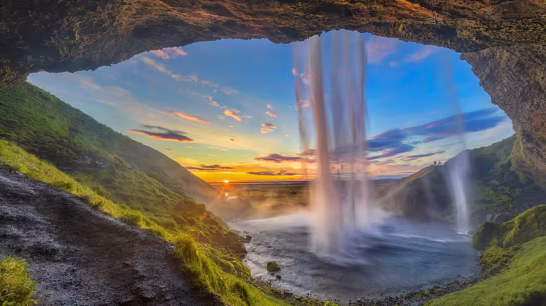 Shot from behind a waterfall with the setting sun in the background