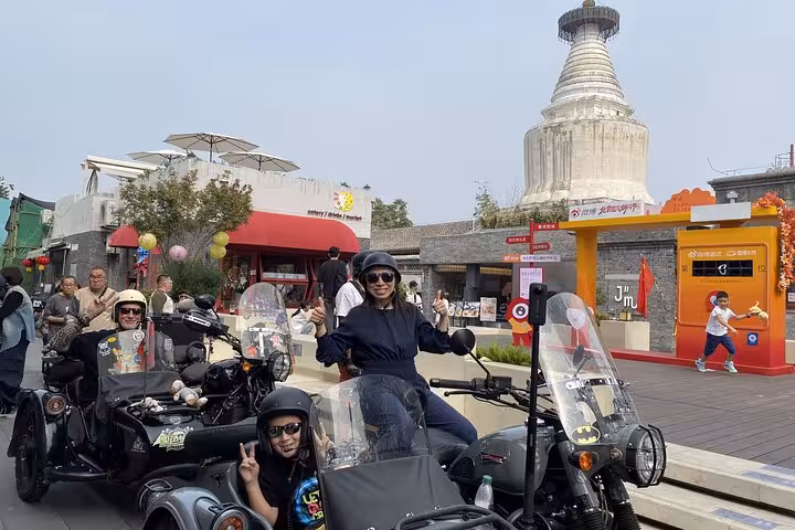 Riders in vintage sidecars explore modern Beijing streets near a historic pagoda, capturing the city's dynamic fusion.
