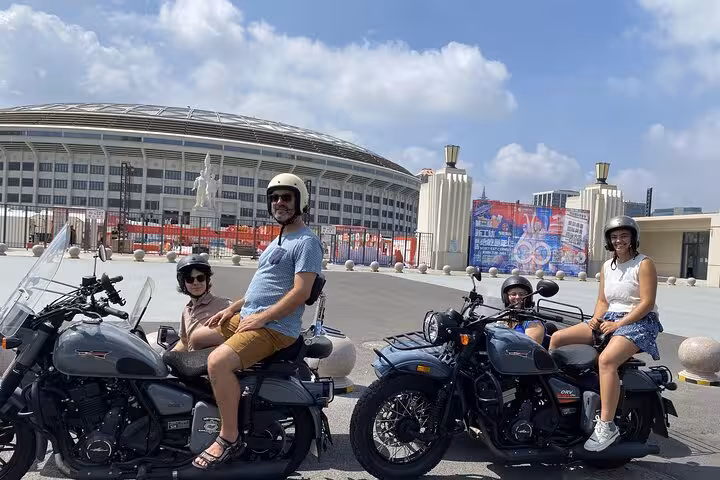 Visitors enjoy a thrilling sidecar ride past Beijing's iconic architecture on a sunny day, embracing local culture.