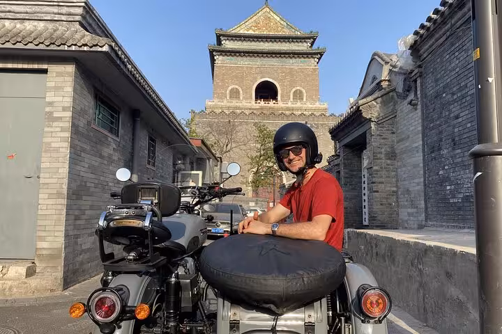 A smiling tourist in a sidecar poses with Beijing's historic architecture on the Ancient & Modern Sidecar Tour.