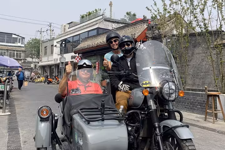 Visitors give thumbs up while riding sidecars through Beijing's traditional neighborhoods on a private guided tour.