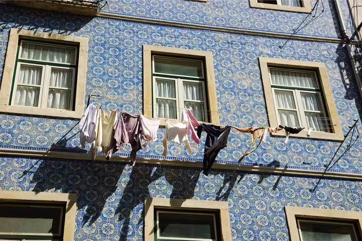 Sunlit clothesline against traditional Portuguese azulejo tiles in Belém, capturing local culture on a private day trip.
