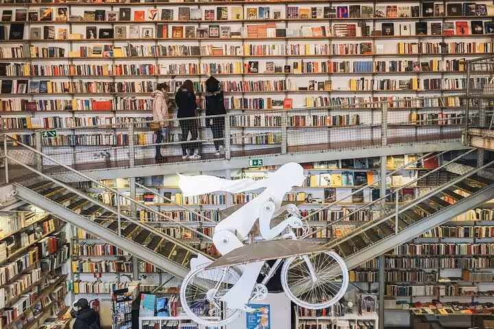 Explore a unique library with layered bookshelves and a quirky cyclist sculpture in Belém on a private tour.