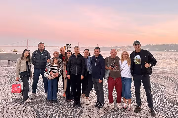 A group of tourists enjoys a scenic sunset view by the Tagus River on a private Belém tour in Lisbon.