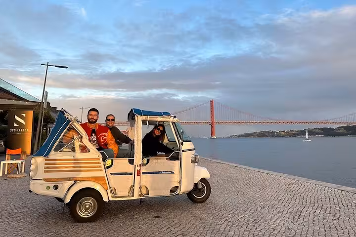 Guests on private Belém tuk tuk tour along Tagus waterfront with 25 de Abril Bridge views and pastries included