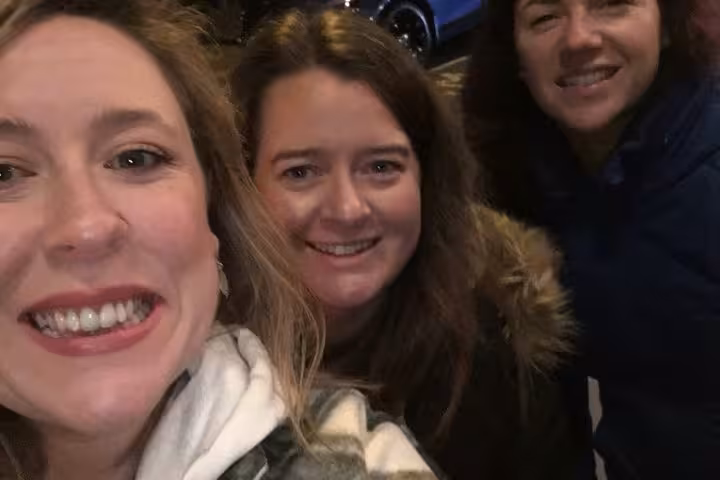 Three smiling women on a nighttime Belfast ghost walking tour street
