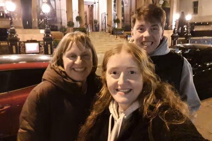 Three smiling people posing at night outside a historic Belfast building during ghost walking tour