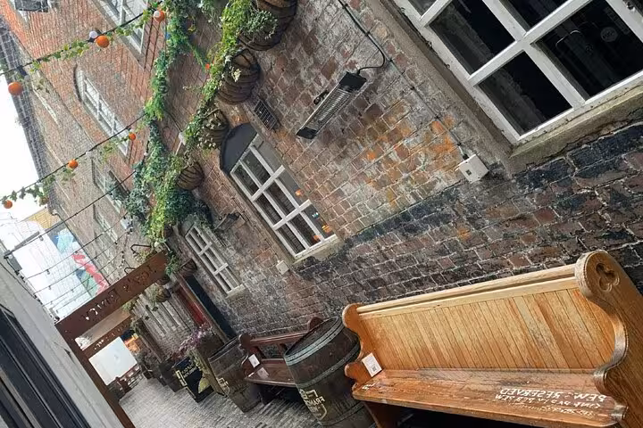 Historic Belfast brick courtyard with ivy-covered walls, wooden barrels, and vintage bench seating