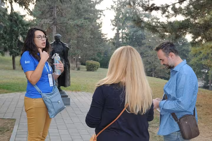 Guide leads a group through a lush park, highlighting key attractions on a Belgrade neighborhood tour.