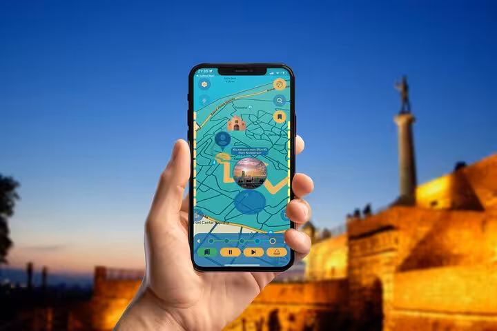 Self-guided Belgrade walking tour app with interactive map at illuminated Kalemegdan Fortress at dusk