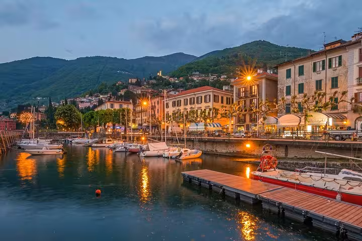 Evening harbor in Bellagio with boats and lakeside lights, Lake Como cruise and day tour from Milan