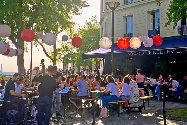 Lively outdoor terrace at Moncoeur Belleville bar with colorful paper lanterns and live band in Paris