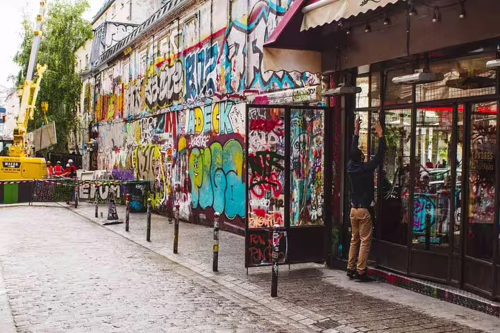 Colorful graffiti-covered walls along a cobblestone street in Belleville neighborhood, Paris