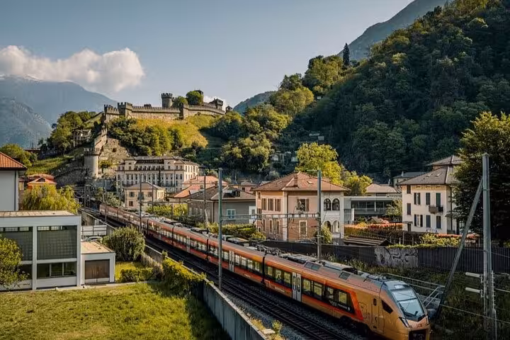 Scenic view of a train passing by Bellinzona castles with mountains in the background on the Ticino tour.