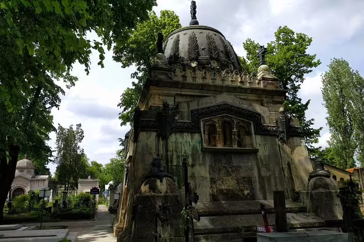Gothic mausoleum with ornate dome and carvings at Bellu Cemetery Bucharest surrounded by trees