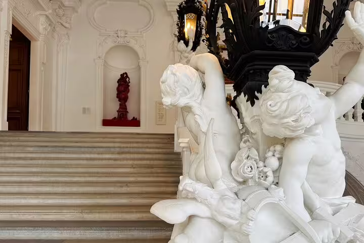 Elegant marble statues adorn the grand staircase of the Belvedere Palace in Vienna, showcasing intricate artistry.
