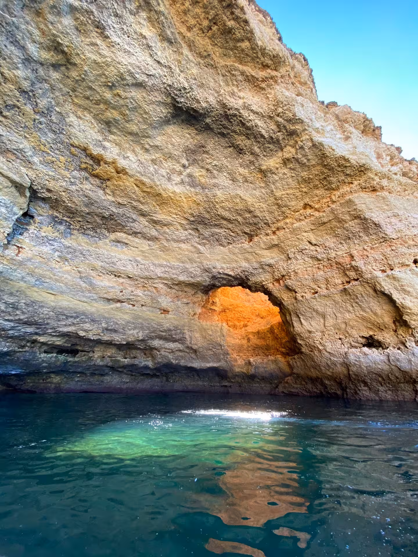 Close-up of rugged Algarve coastline and sea cave entrance near Benagil, with turquoise Atlantic water reflecting cliffs