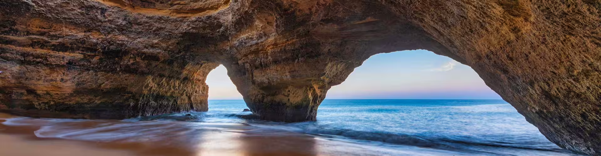 Stunning view of the Benagil Cave with its iconic arches and serene ocean backdrop in Algarve, Portugal, perfect for exploring natural wonders.