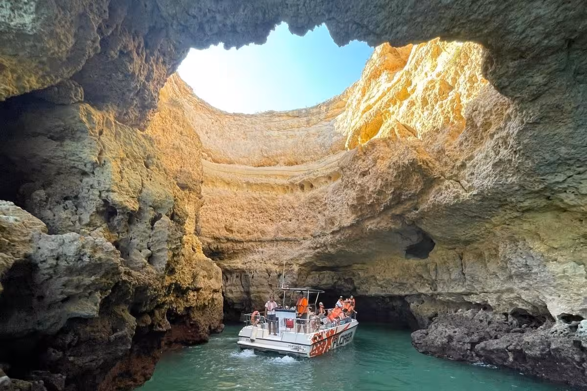 Algarve boat tour group exploring the breathtaking Benagil Cave interior with turquoise waters and dramatic limestone ceiling opening