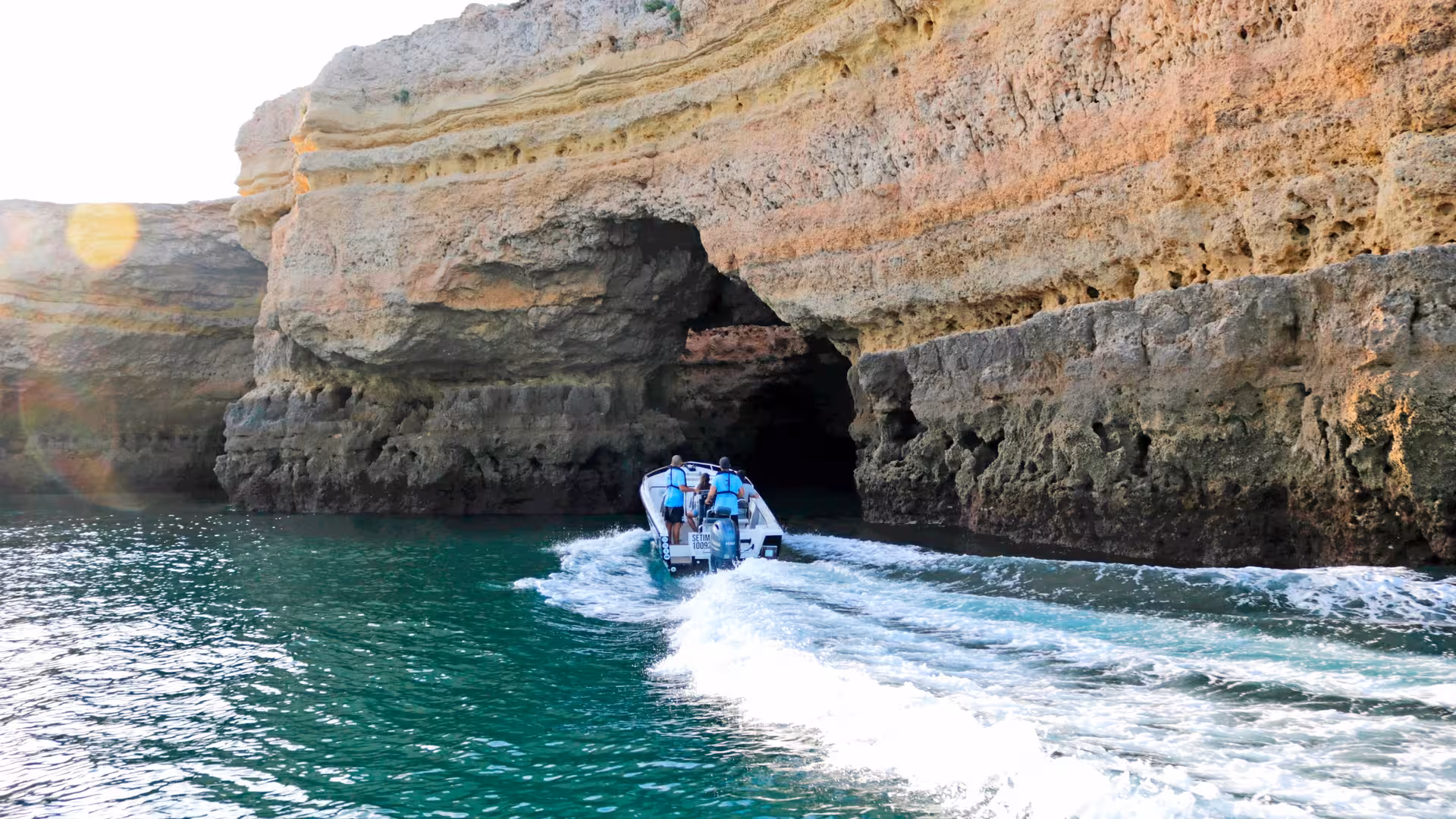 Small boat on a private Benagil cave tour gliding toward dramatic Algarve sea cliffs and turquoise Atlantic waters
