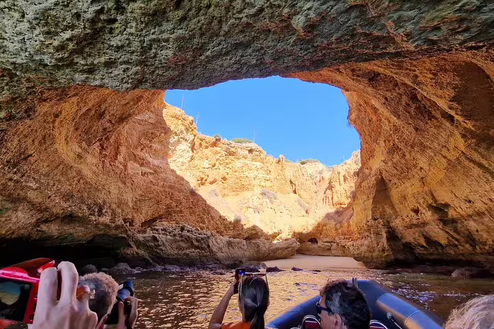 People explore the stunning Benagil Cave by boat on a sunny day during a private two-day tour from Lisbon to Algarve.