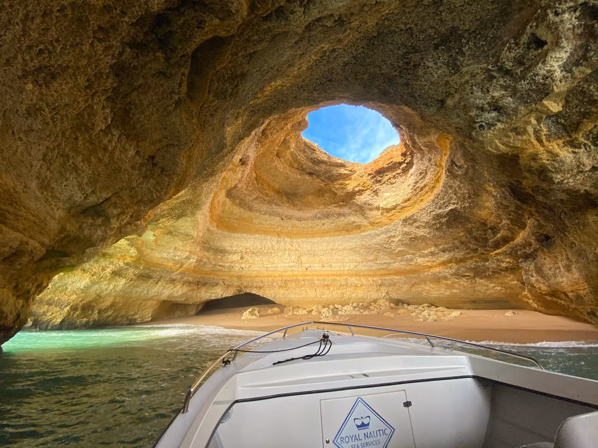 Boat entering Benagil Cave in Algarve, Portugal, revealing golden rock dome, secret beach and turquoise Atlantic waters on guided tour