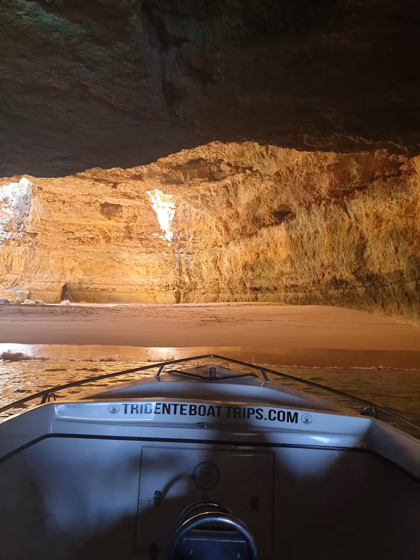 Private Benagil Cave boat tour from Armacao de Pera showing golden limestone interior with sandy beach inside the cave.