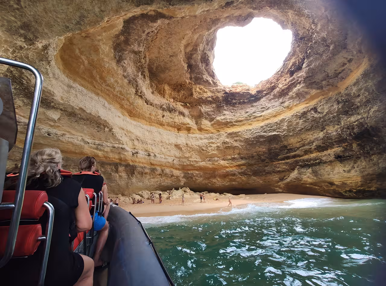 Visitors explore the stunning Benagil Cave by boat, marveling at its unique rock formations and sandy beach.